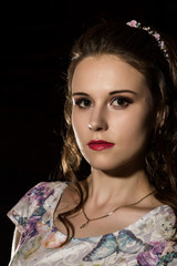 young elegant woman with professional hairstyle poses on a dark background.