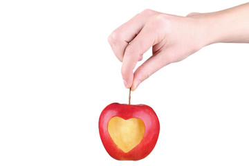 Female hands holding red apple with cutout heart shape on white background