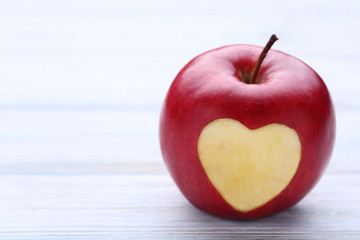 Red apple with cutout heart shape on wooden table