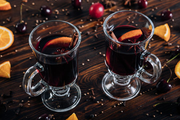 Mulled wine with spices and fruits on wooden background