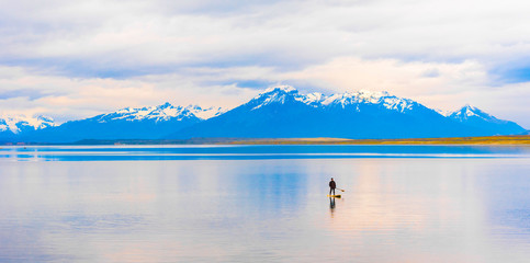 PUERTO NATALES, CHILE - JANUARY 11, 2018: A view of the mountain landscape. A man on a board with...