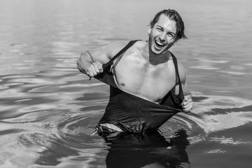 Handsome man in water, sexy guy showing muscular fit body. Concept os sport life of men. Muscular...