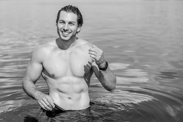 Handsome man in water, sexy guy showing muscular fit body. Concept os sport life of men. Muscular...