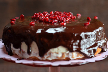 Fruit cake with chocolate topping. Pomegranate fruit on the cake
