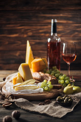 different types of cheeses, grapes and pears on wooden tabletop