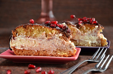 A piece of cake with cream and chocolate sauce on a plate. Pomegranate fruit on chocolate glaze