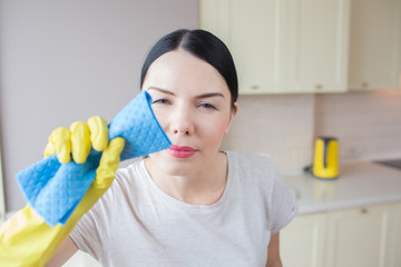 Horizontal portrain of woman stands and cleans lenz of camera. She is very concentrated on that. Girl is cleaning it with blue rag. She has her hands in yellow gloves.