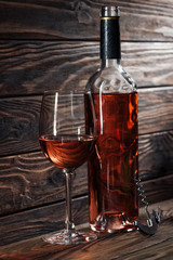 wine bottle, glass of wine and corkscrew on wooden table