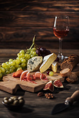 different types of cheeses and prosciutto on cutting board