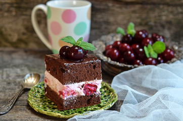 Chocolate sponge cake filled with whiped cream with cherries on wooden background