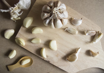 Fototapeta na wymiar Garlic Bulb and Garlic Cloves on Wooden chopping board placed on the MDF wooden plate board Texture Background.