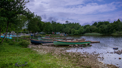 Landscape side view of dozen aligned small boats anchored to the shore.