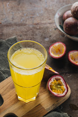Passion fruits in half and juice on the rustic background. 