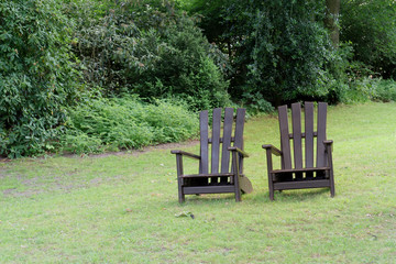 Two wooden chairs for relaxing on the green meadow in a park