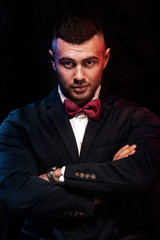 Portrait of a charming mature businessman dressed in suit posing while standing and looking at camera isolated over black background