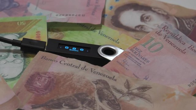 Physical metal Bitcoin currency over bolivar bills. Virtual internet money with Venezuelan banknotes. Digital coin cyberspace, cryptocurrency. BTC golden coin as symbol of electronic virtual money. 4K