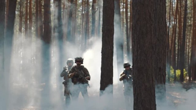 Soldiers in full ammunition takes a position in a smoky forest