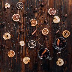 Mulled wine with spices and dried fruits on wooden background