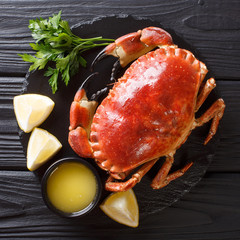 tasty boiled whole brown crab with sauce, lemon and parsley on a stone board close-up. top view © FomaA