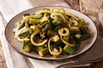 Vegan cuisine: spicy okra fried with onion close-up on a plate. horizontal
