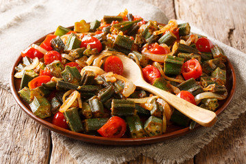 Serve Organic okra with tomatoes and onion close-up on a plate on the table. horizontal, rustic style