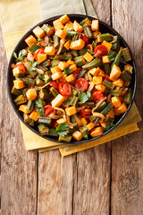 Traditional recipe ragout from okra, sweet potato, tomatoes, onions and herbs close-up on a plate. Vertical top view