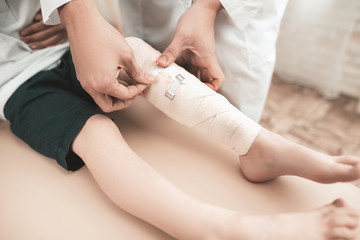 Obraz na płótnie Canvas Arabian Doctor Is Bandaging Little Child's Leg.
