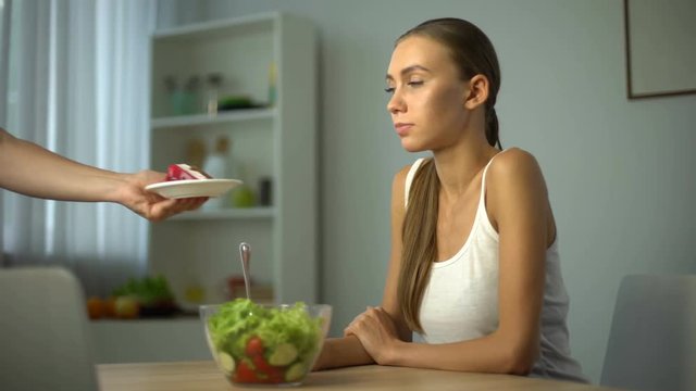 Slender girl prefers salad instead of cake, vegetarian meal, low-calorie food