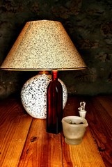 A reading lamp on a table of wood and herbs. Glass grinder, old bottle for drops and red tin for...
