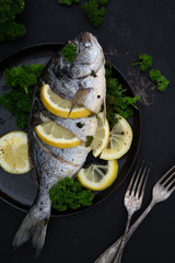 Teller mit frisch gekochte Dorade (Fisch) auf einem dunklen Untergrund