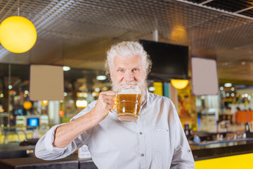 Pleasant relaxation. Happy joyful man being in a great mood while resting with a glass of beer in the pub