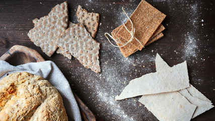 Rye bread and  rye crackers  on wooden brown board sprinkled with rye flour