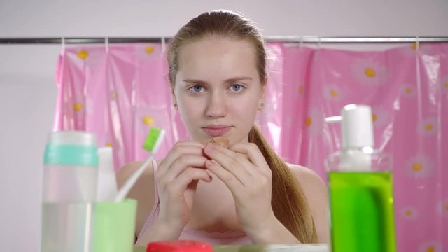 Teenage girl putting dental retainer on teeth in bathroom