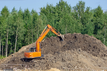 Orange excavator loads the soil