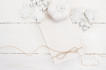 linen rope, white pumpkin, berries and leaves, mock up autumn white sheet of paper on a wooden background. Greeting card for Thanksgiving Day in rustic style with space for your text. Flat lay. Top