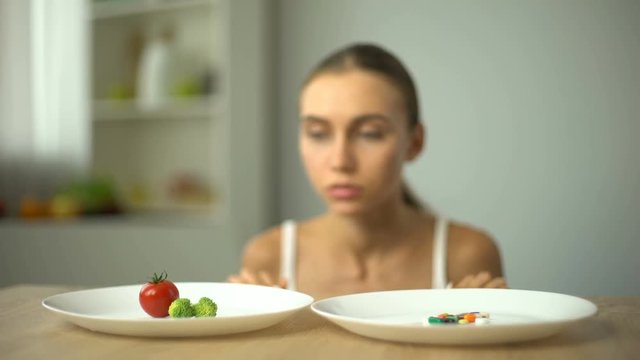 Girl choosing between vegetables and pills, healthy diet vs weight loss drugs