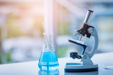 Microscope and Beaker on table in Laboratory. Science chemistry concept. Blue tone