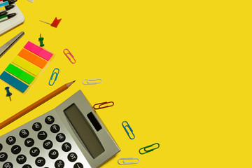 multiple school and office suplies and gadgets lying diagonally on a yellow background. free...