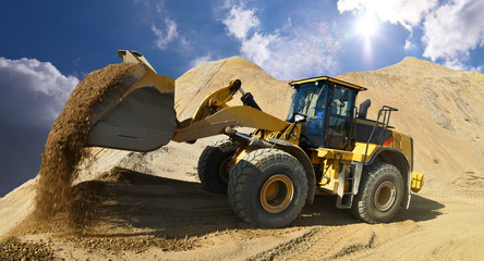 Wheel loader in a gravel pit during mining - heavy construction machine in open cast mining - obrazy, fototapety, plakaty