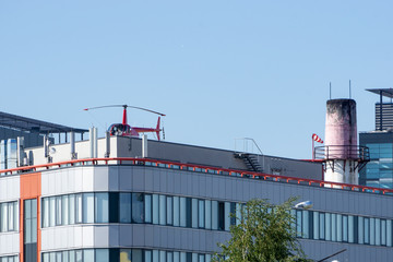 Red helicopter on the roof of an office building.