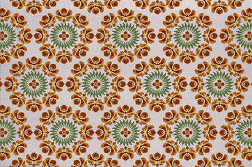 Seamless cotton fabric of round embroidery with stylized orange flowers, wreath of green leaves and a flower in the center

