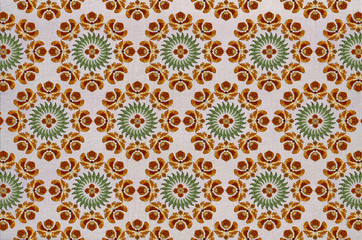 Seamless cotton fabric of round embroidery with stylized orange flowers, wreath of green leaves and a flower in the center

