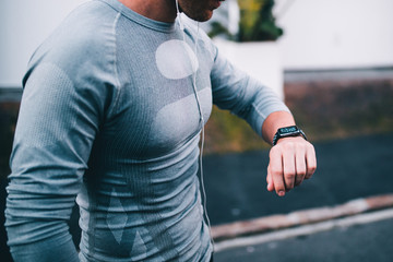 athletic man looking at smart watch while doing outdoor fitness