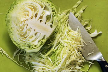 chopped cabbage on wooden board, close-up, on green background