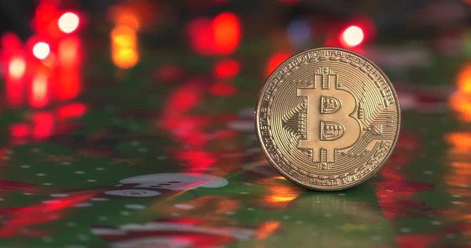 Golden Bitcoin currency. Festive atmosphere. Colorful Christmas tree lights in the background. BTC is a cryptocurrency and is the first decentralized peer-to-peer payment network.4K, Panning, Closeup.