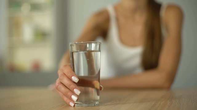 Smiling girl offers glass of water, keeps body hydrated, moisturized skin