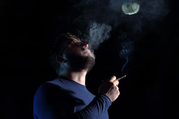 man brunette with a cigarette in the dark, a lot of smoke