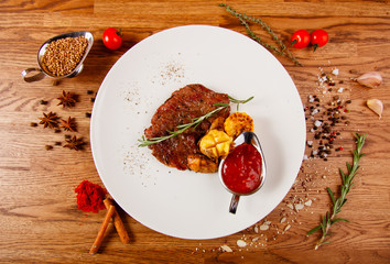  Grilled meat whale in a white plate on the table, with many condiments and salads.