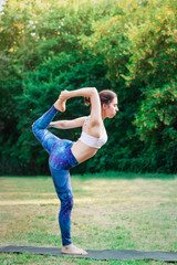 Obraz na płótnie Canvas Slim young woman practicing yoga in nature. Natarajasana pose.