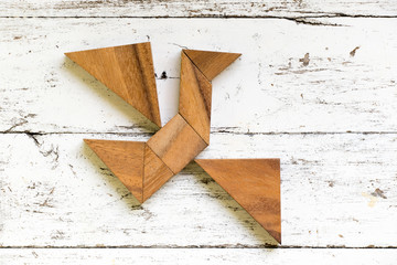 Tangram puzzle in flying bird shape on old white wood background (Concept for freedom, new...